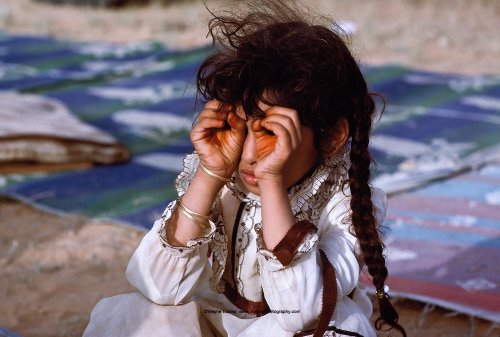 فتاة تصنع منظار اليد. يسارع الأطفال إلى تقليد المهارات التي لوحظت من الكبار. في مخيم المرة في رمال الدهانا بالمملكة العربية السعودية.